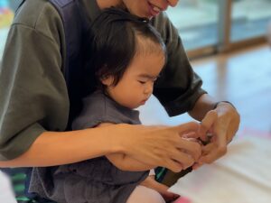 職員の先生が園児と一緒に絵の具のスタンプを押している様子
