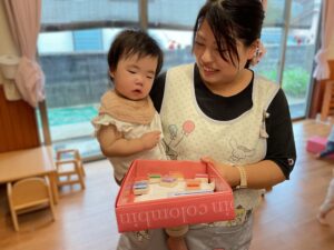 どの色にしようか職員の先生が絵具の入った箱を持ち、園児と相談している
